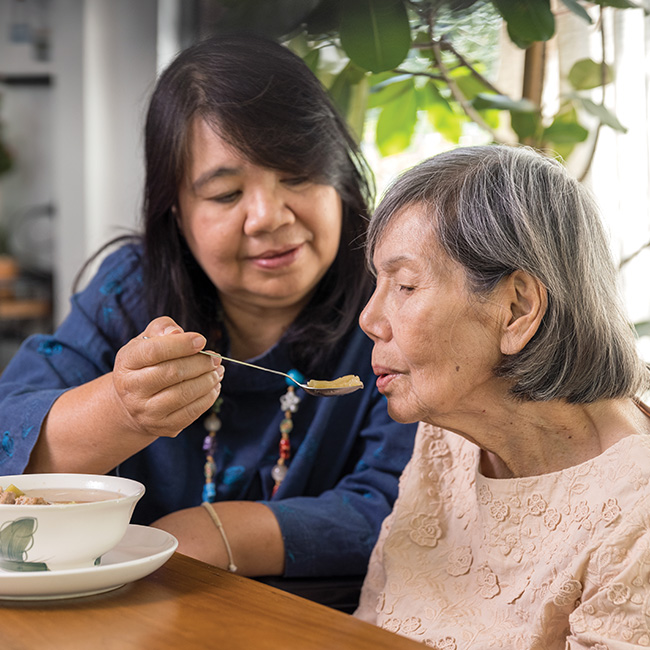 Caregiving feeding an elderly woman soup